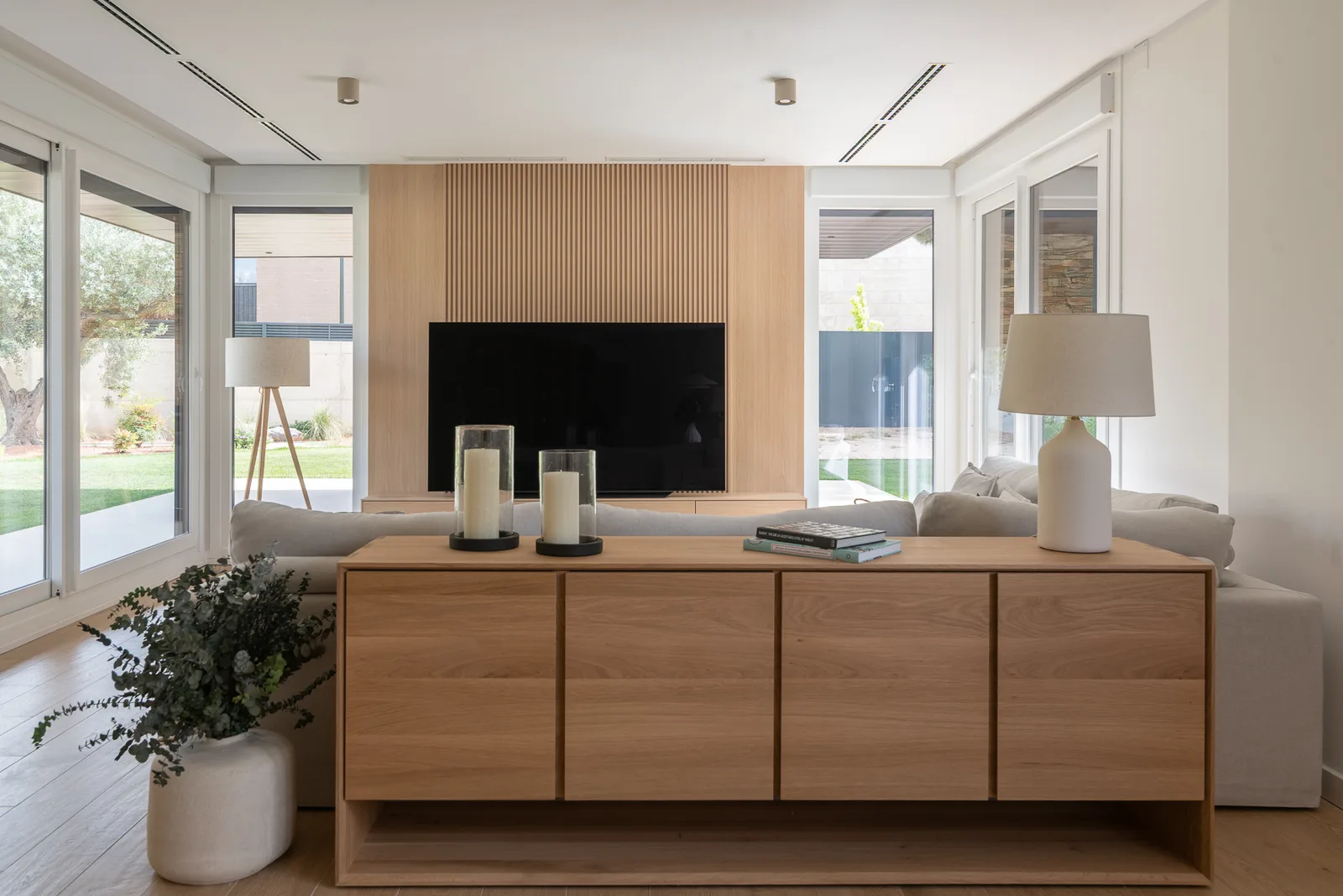 Salón con panel de madera ranurada y mueble bajo de roble